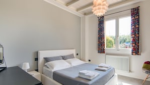 Un dormitorio moderno con cama, mesitas de noche, un escritorio y una ventana con cortinas.