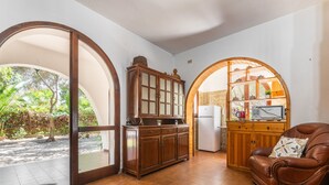 A kitchen with wooden cabinets, a refrigerator, and a television on a wooden shelf. - Sant'Andrea by Interhome (Capitana)