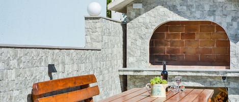 A wooden bench and table with a bottle and glass, set against a stone wall with a brick archway.