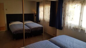 Un dormitorio con dos camas, un armario y una ventana con cortinas.