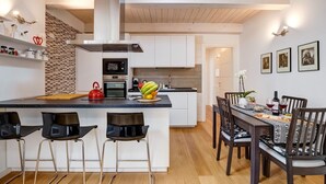 A modern kitchen with a central island, bar stools, and a dining area with a table set for four. - Civico36 Feels Like Home (Cagliari)