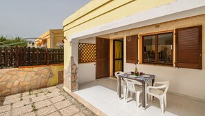 Eine Terrasse mit Tisch und Stühlen, eine Steinmauer und ein Holzzaun.