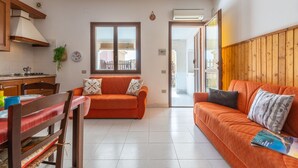 Ein modernes Wohnzimmer mit einer Couch, einem Esstisch mit Stühlen und einer Küchenzeile mit Herd.
