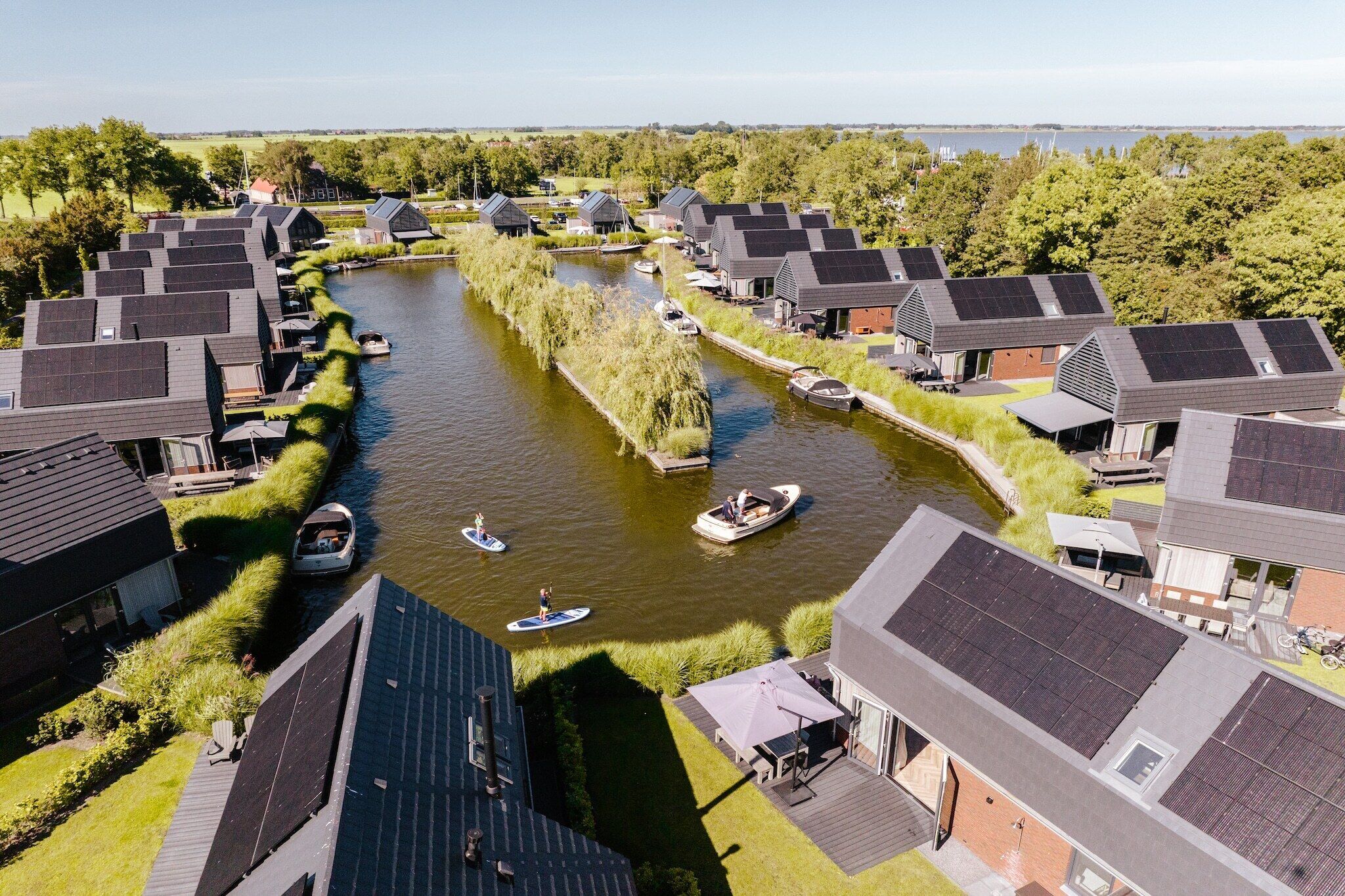 A riverside property with multiple houses, a canal, and boats.