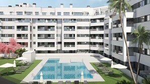 A modern multi-story hotel with a central swimming pool surrounded by lounge chairs and umbrellas.