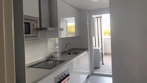 A modern kitchen with a built-in oven, microwave, and stainless steel sink.