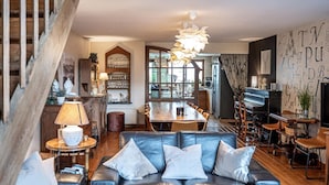 Una sala de estar acogedora con un sofá de cuero, una mesa de comedor y un piano.