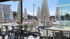 Un área de estar al aire libre con mesas y sillas, sombrillas y vistas a un edificio moderno.