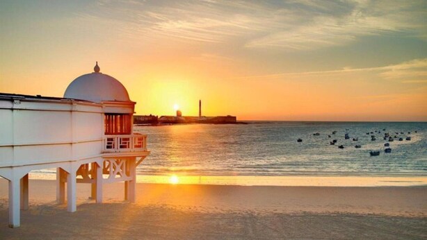 Un edificio costero con cúpula y balcón que da al mar al atardecer.