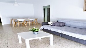 Una sala de estar moderna con una mesa de centro blanca, sofá gris y sillas de madera.