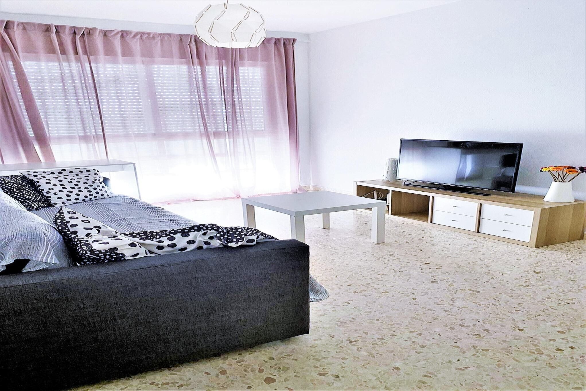 A modern living room with a grey sofa, a white coffee table, and a flat-screen TV on a wooden cabinet.