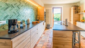 A modern kitchen with a herringbone tile backsplash, wooden cabinets, and a central island. - Stunning holiday home in Theux (Theux)