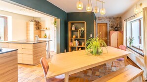 A modern kitchen with a wooden table, chairs, and a bench. There is a bookshelf with various items and a potted plant. - Stunning holiday home in Theux (Theux)