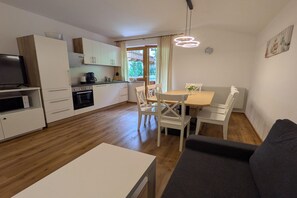 A modern kitchen with white cabinets, a dining area with a table and chairs, and a living room with a sofa.