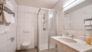 A modern bathroom with a glass-enclosed shower, a white toilet, and a marble sink.
