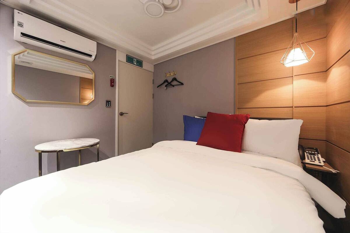 Una habitación de hotel con cama, mesita de noche y lámpara colgante.