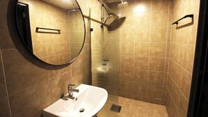 Un bagno con uno specchio tondo, un lavandino e una doccia.