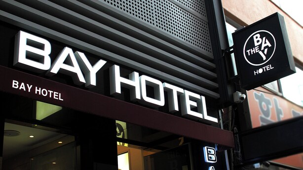 Segnaletica di un hotel con il nome 'Bay Hotel' e un'altra insegna più piccola che indica 'Bay Hotel' con un logo.