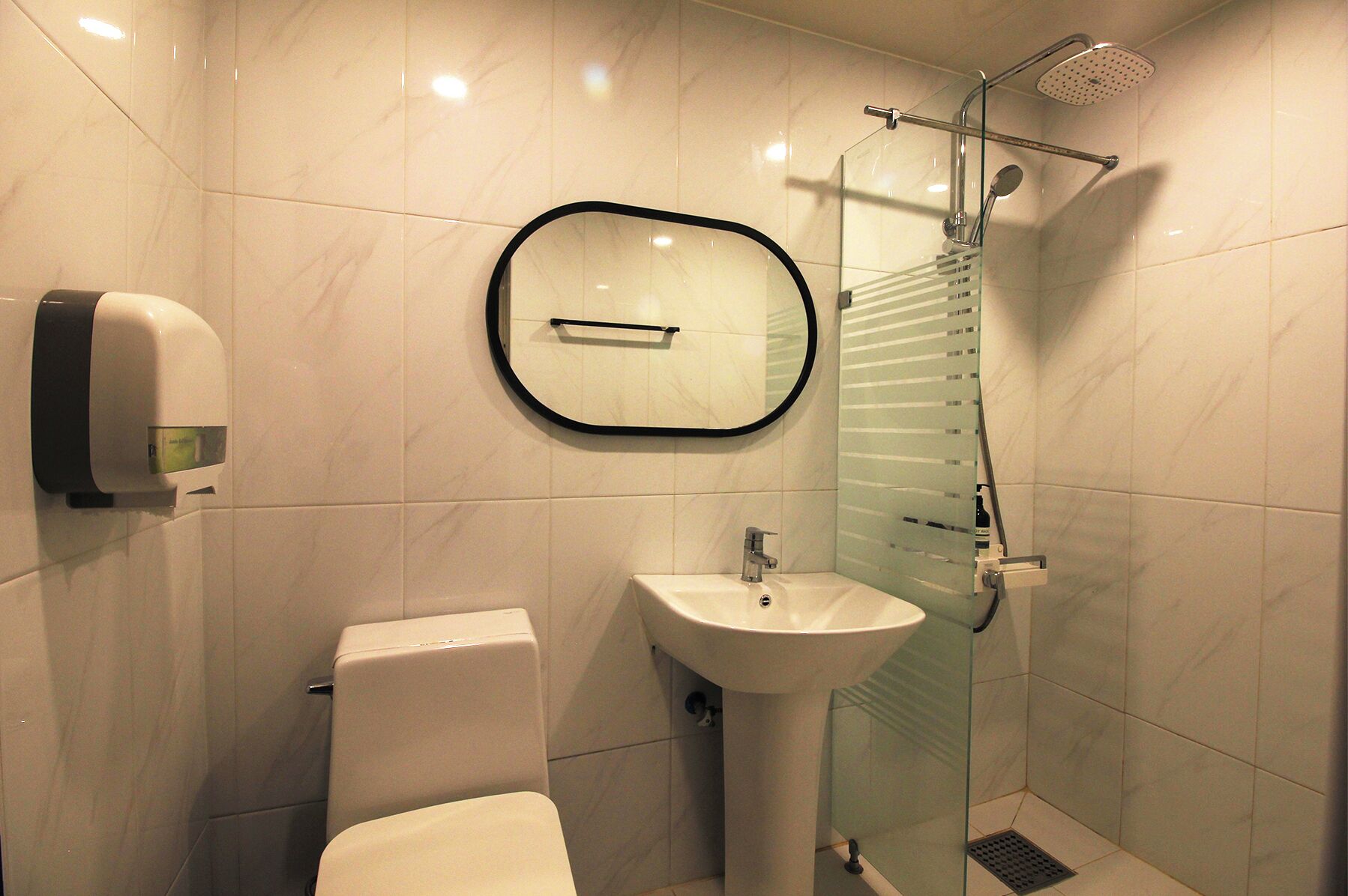 Un baño con inodoro, lavamanos y cabina de ducha de cristal.