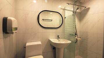 Un baño con inodoro, lavamanos y cabina de ducha de cristal.