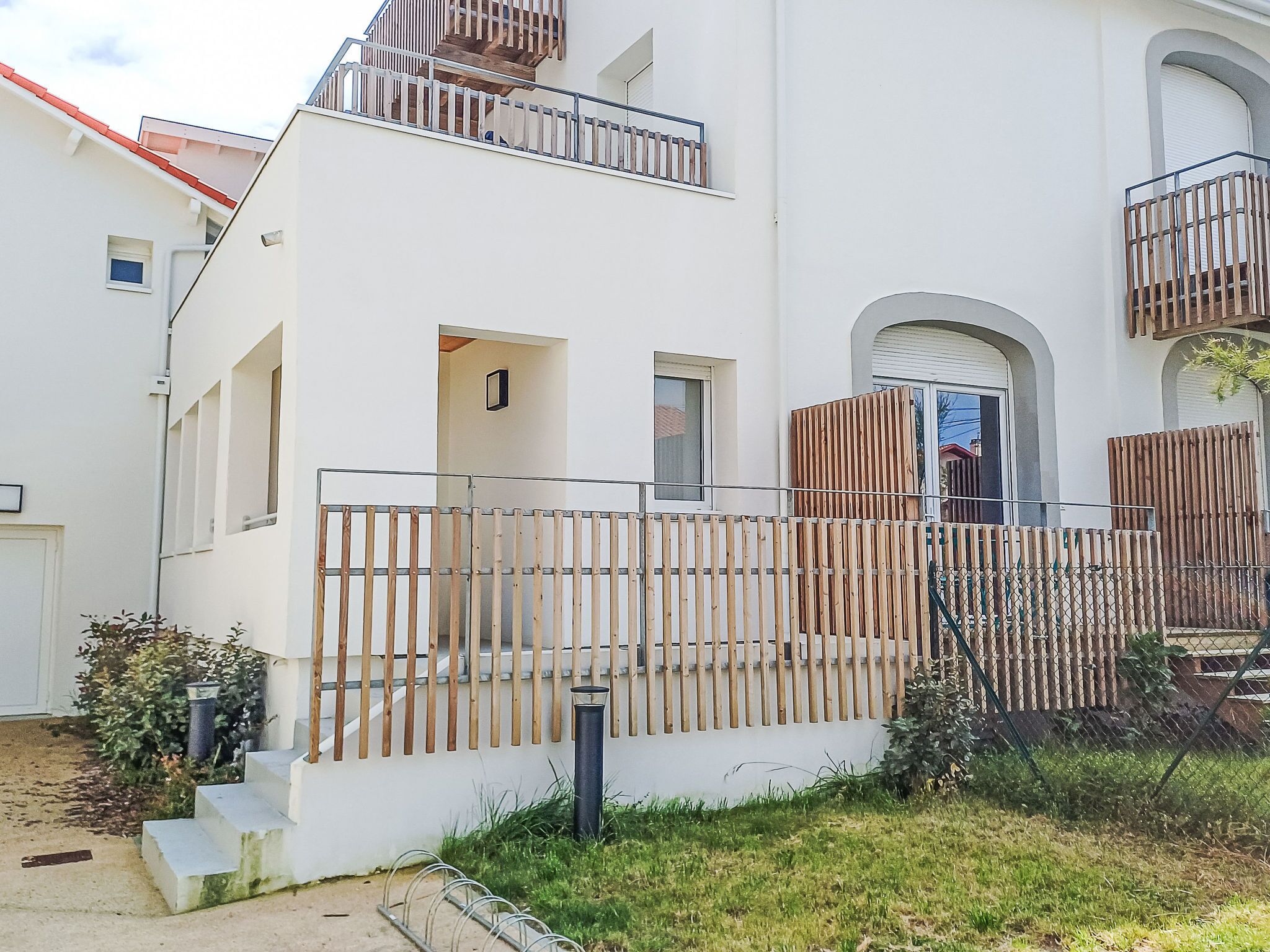 A white building with a wooden fence, a small garden, and a visible door labeled '1'.
