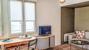 Una sala de estar moderna con comedor, televisión y sofá.