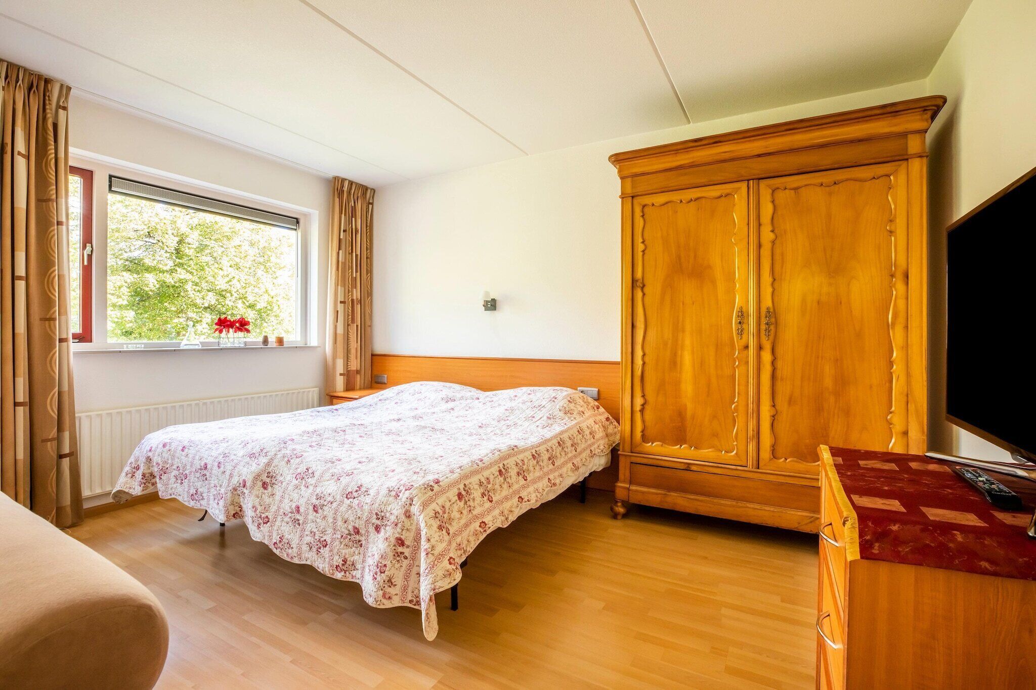 A bedroom with a bed, wooden wardrobe, and a television.