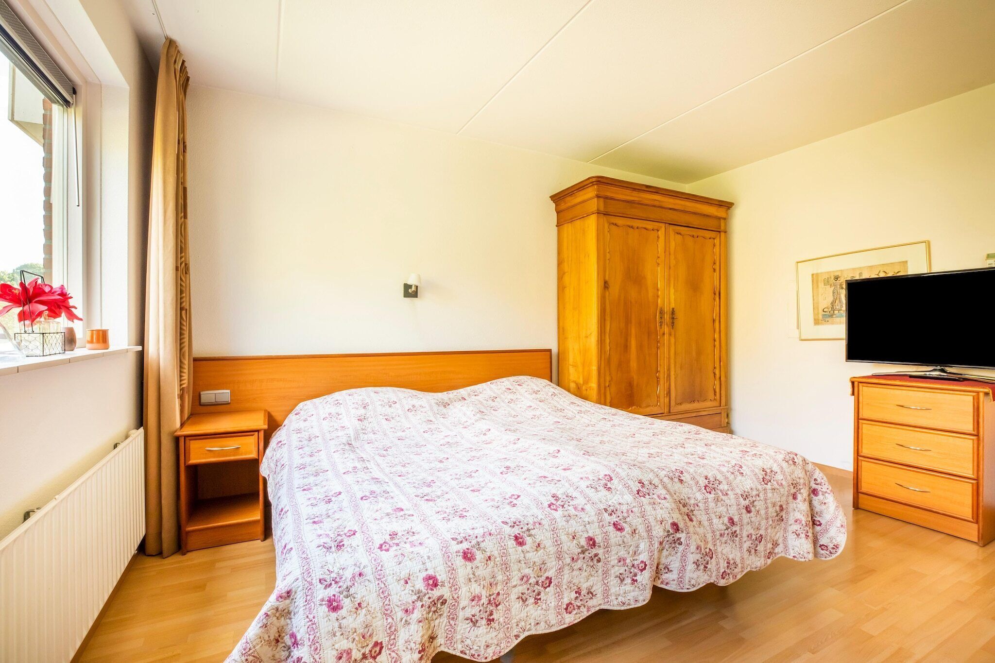Ein Schlafzimmer mit einem Bett, einem Holzschrank, einem Nachttisch und einem Fernseher.