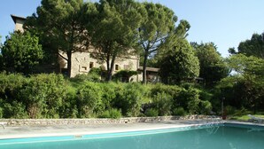 A pool area with a stone building in the background, surrounded by trees and greenery. - Charming Family Retreat in Umbria (Mantignana)