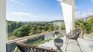 Een balkon met vrij uitzicht op een kustlandschap, met bomen en een weg.