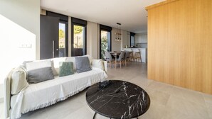 Een moderne woonkamer met een witte bank, een salontafel van zwart marmer en een houten roomdivider.