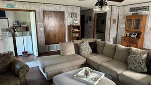 Una sala de estar con un sofá seccional, una mesa de centro y una estantería.