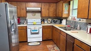Una cocina con armarios de madera, un refrigerador de acero inoxidable, una estufa blanca y un tostador.