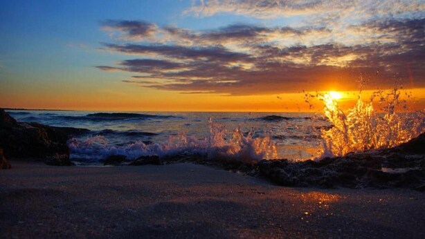 Un coucher de soleil sur l’océan, avec des vagues qui déferlent sur le rivage.