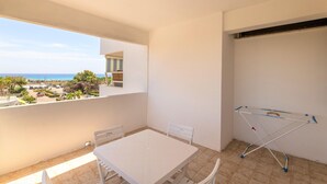 Un balcon avec une table et des chaises, un étendoir et une vue sur la mer et les bâtiments.