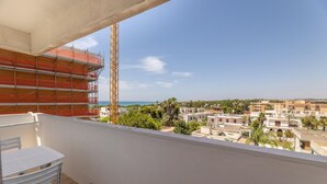 Ein Balkon mit Blick auf eine Küstenstadtlandschaft, darunter Gebäude und ein klarer Himmel.