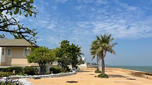 A paved walkway with palm trees and a building in the background. - RIM Chaam By RoomQuest (Cha-am)