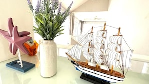 A model ship on a table, a potted plant, and a starfish decoration. - RIM Chaam By RoomQuest (Cha-am)