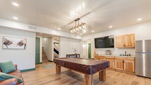 Un salon moderne avec une table de billard, des meubles en bois et un téléviseur à écran plat.