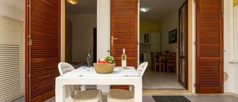 A dining area with a table, two chairs, a fruit bowl, and a bottle of wine.