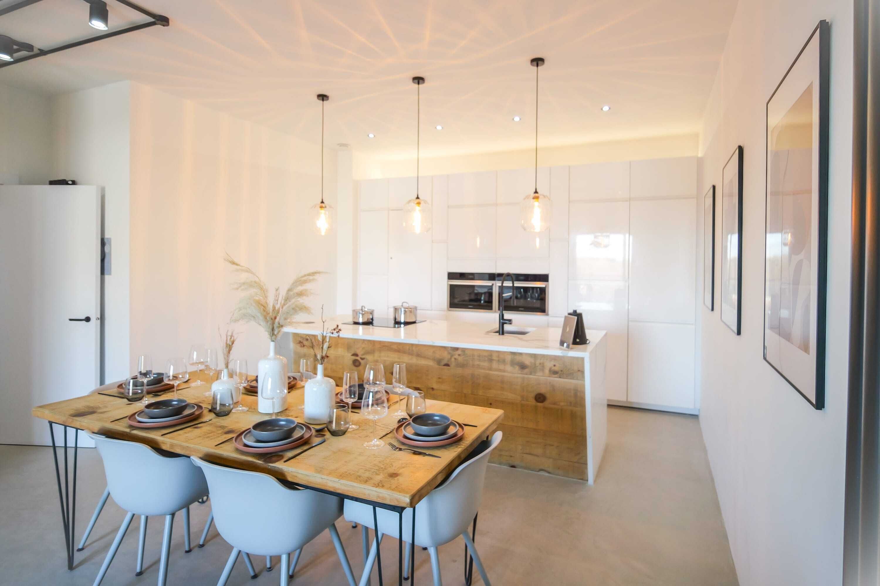 A modern kitchen with a wooden island, pendant lighting, and white cabinetry.