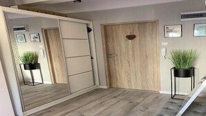 A modern room with a sliding door, a wooden floor, and two potted plants. - Apartment in Gdańsk near Brzeźno Pier (Gdańsk Brzeźno)