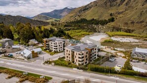 A residential area with modern apartment buildings, a main road, and a river. - Modern Apartment Near Coronet Peak Ski Field (Queenstown)