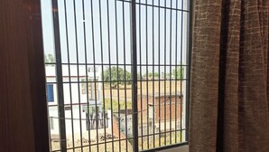 A room with a barred window overlooking a courtyard. - Soni Homestays (Khalilabad)