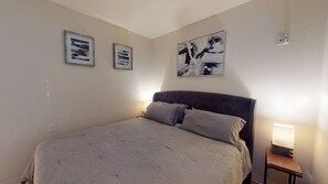 Un dormitorio con una cama, una mesita de noche y una obra de arte colgada en la pared.