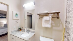 Un baño de hotel con lavamanos, espejo, toallero y retrete.