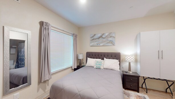 A bedroom with a bed, a nightstand, a lamp, a wardrobe, and a mirror. - RD102 - Home|Yard|12mi to Convention Ctr|Sleeps 6 (Richardson)