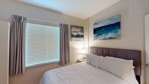 A bedroom with a bed, curtains, a painting, and a nightstand.