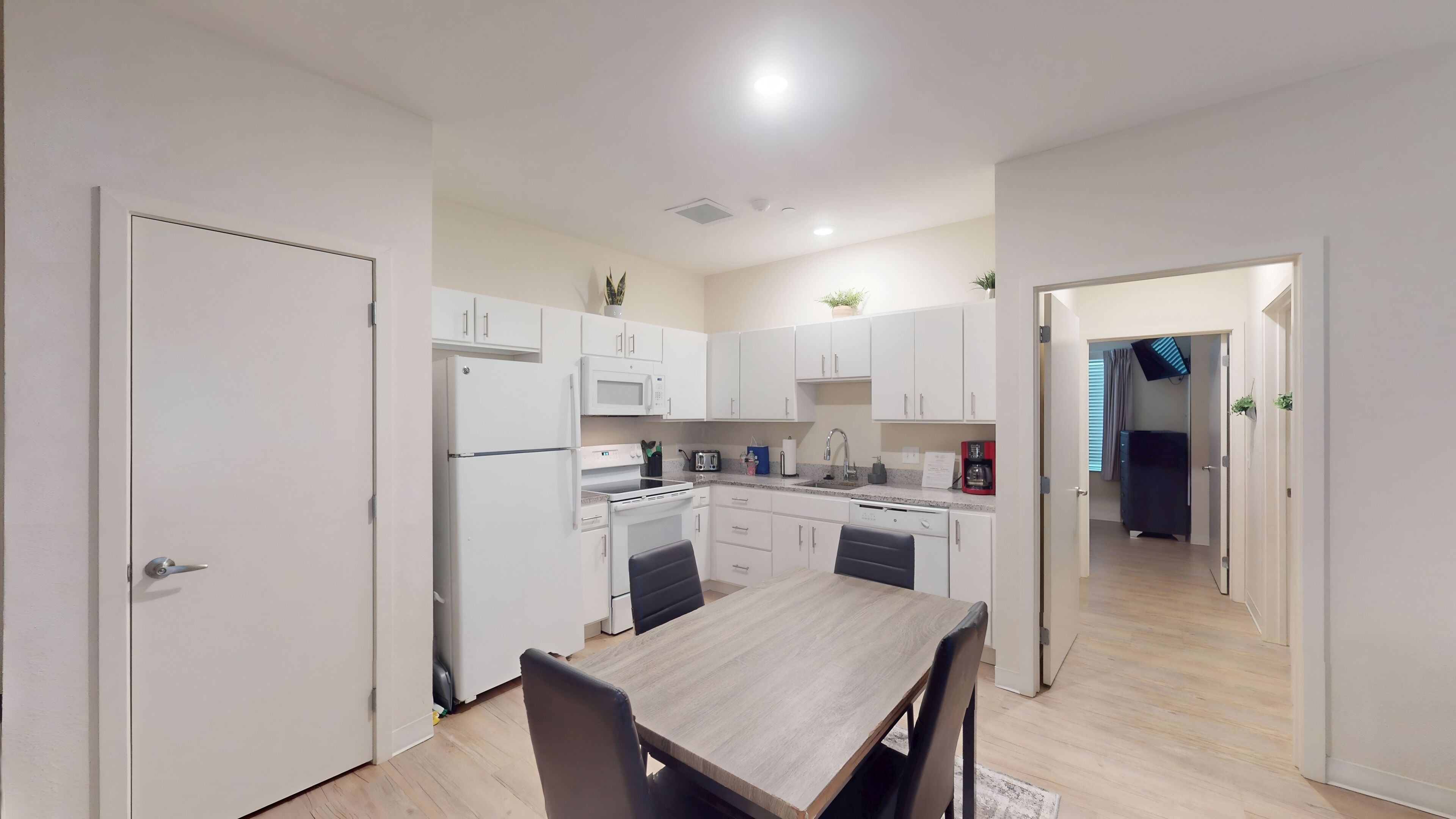 A modern kitchen with white cabinets, a dining table, and chairs.