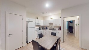 Una cocina moderna con armarios blancos, una mesa de comedor y sillas.